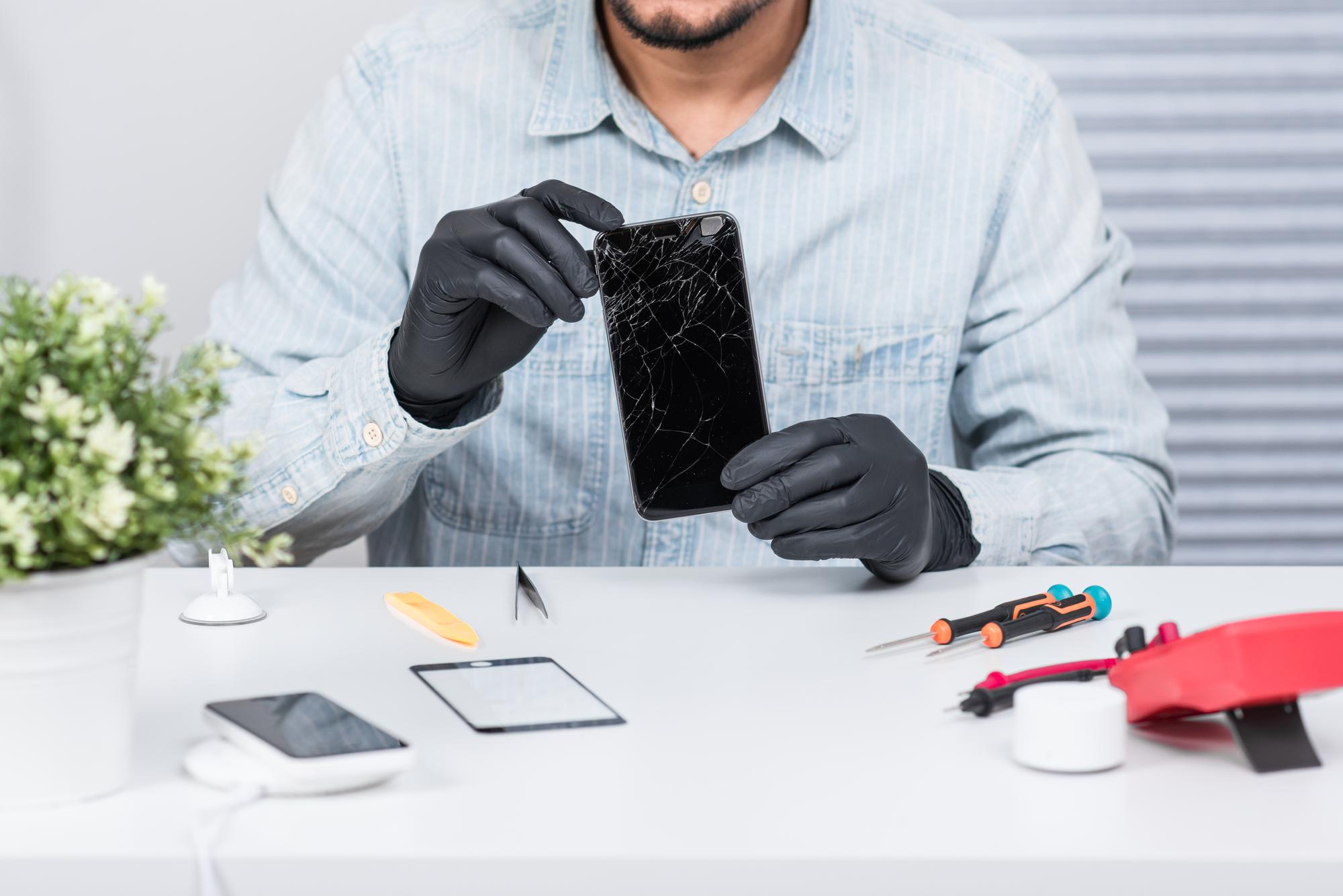 iPhone reparatie Harlingen — gecertificeerde technicus met beschermhandschoenen repareert iPhone